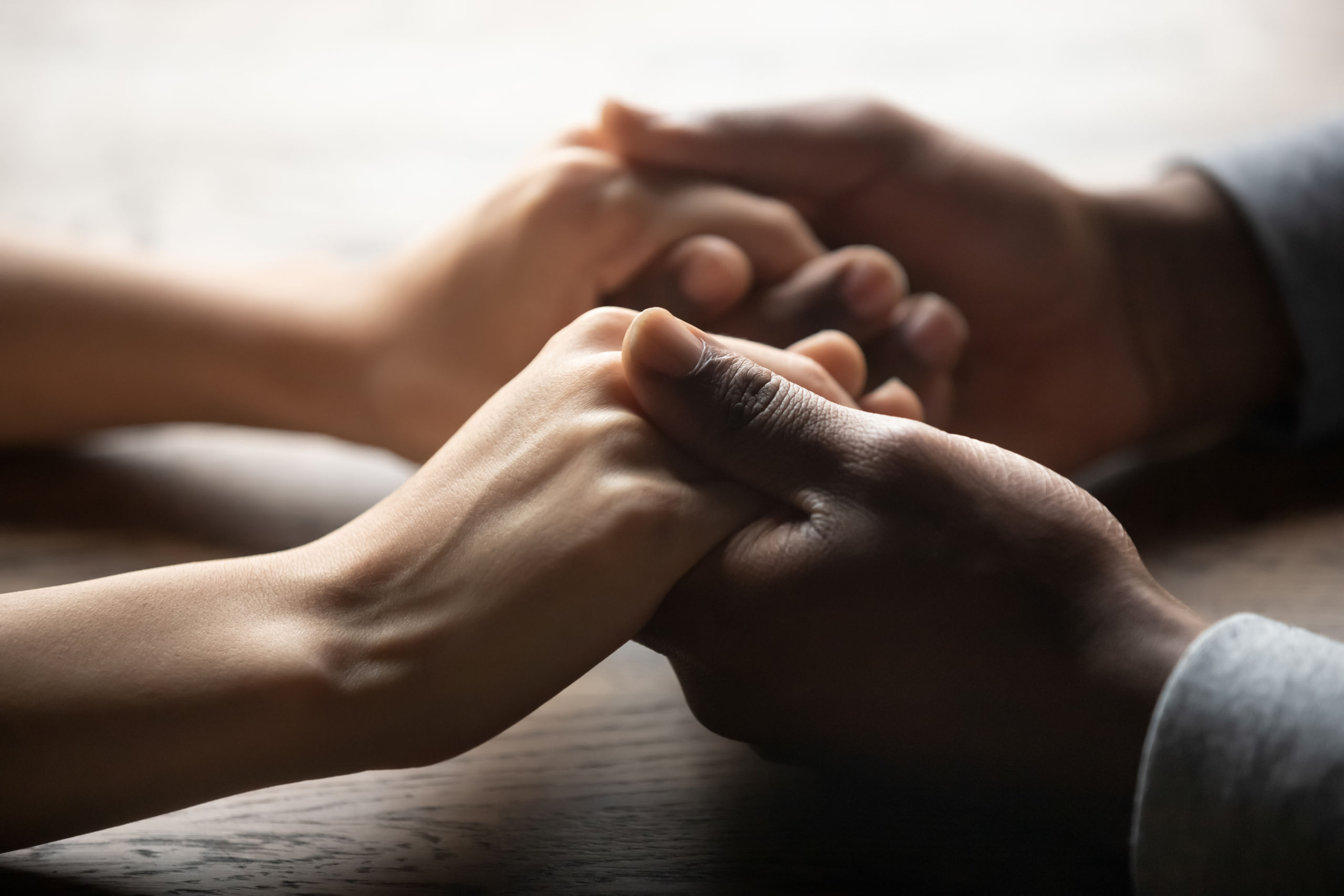 Mixed ethnicity couple holding hands on table, close up view